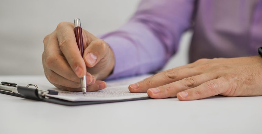 Young man holding a pencil, writing on a paper in the diary Young man holding a pencil, writing on a paper in the diary